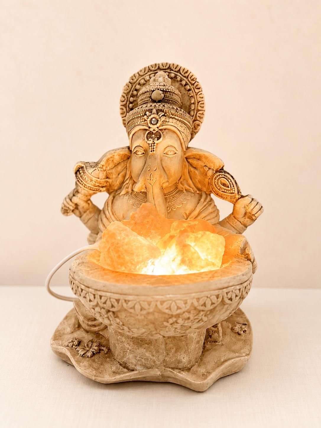 Figura de Ganesha junto a una lámpara de sal encendida, en luz ámbar.